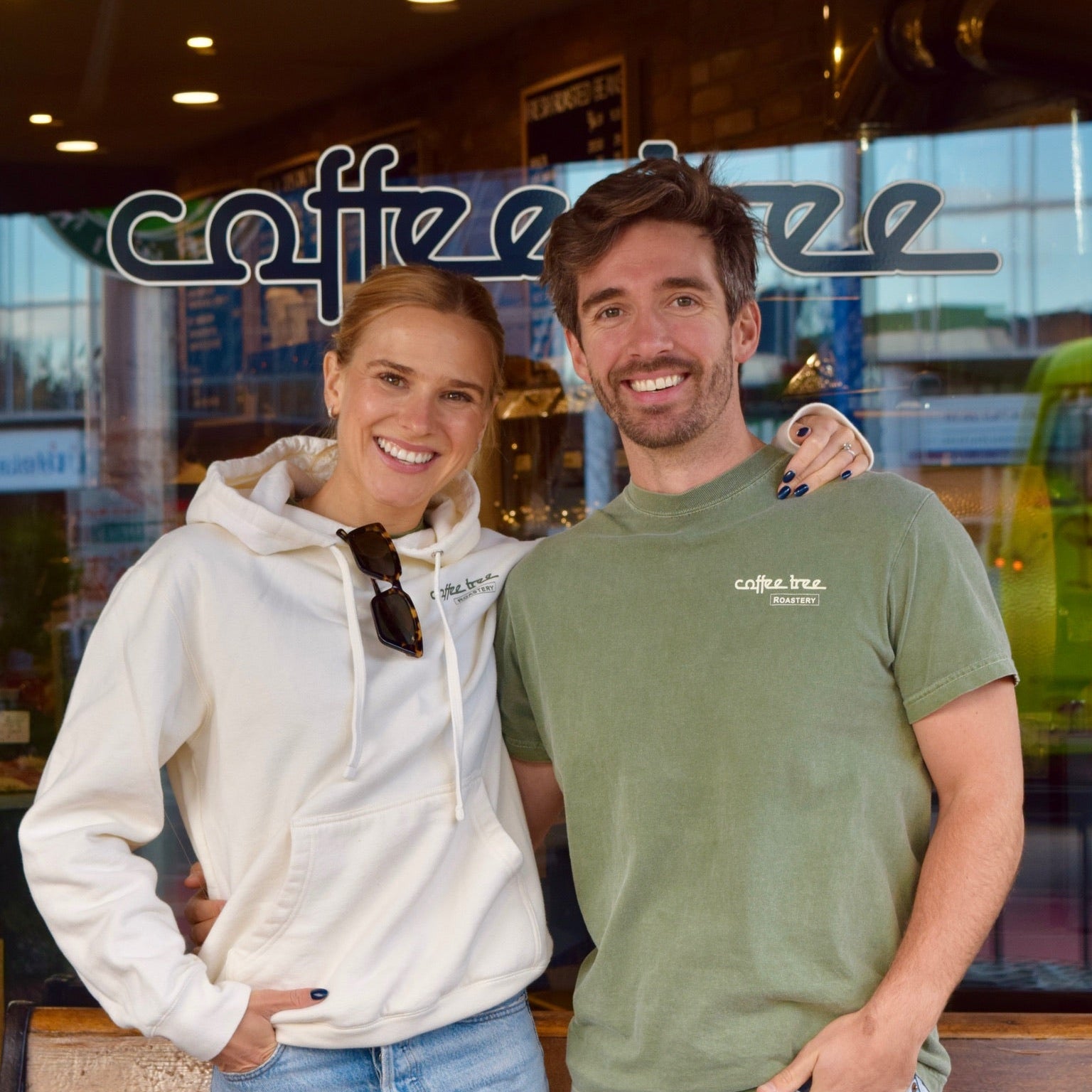 Two people standing in front of a coffee shop with 'coffee' branding.