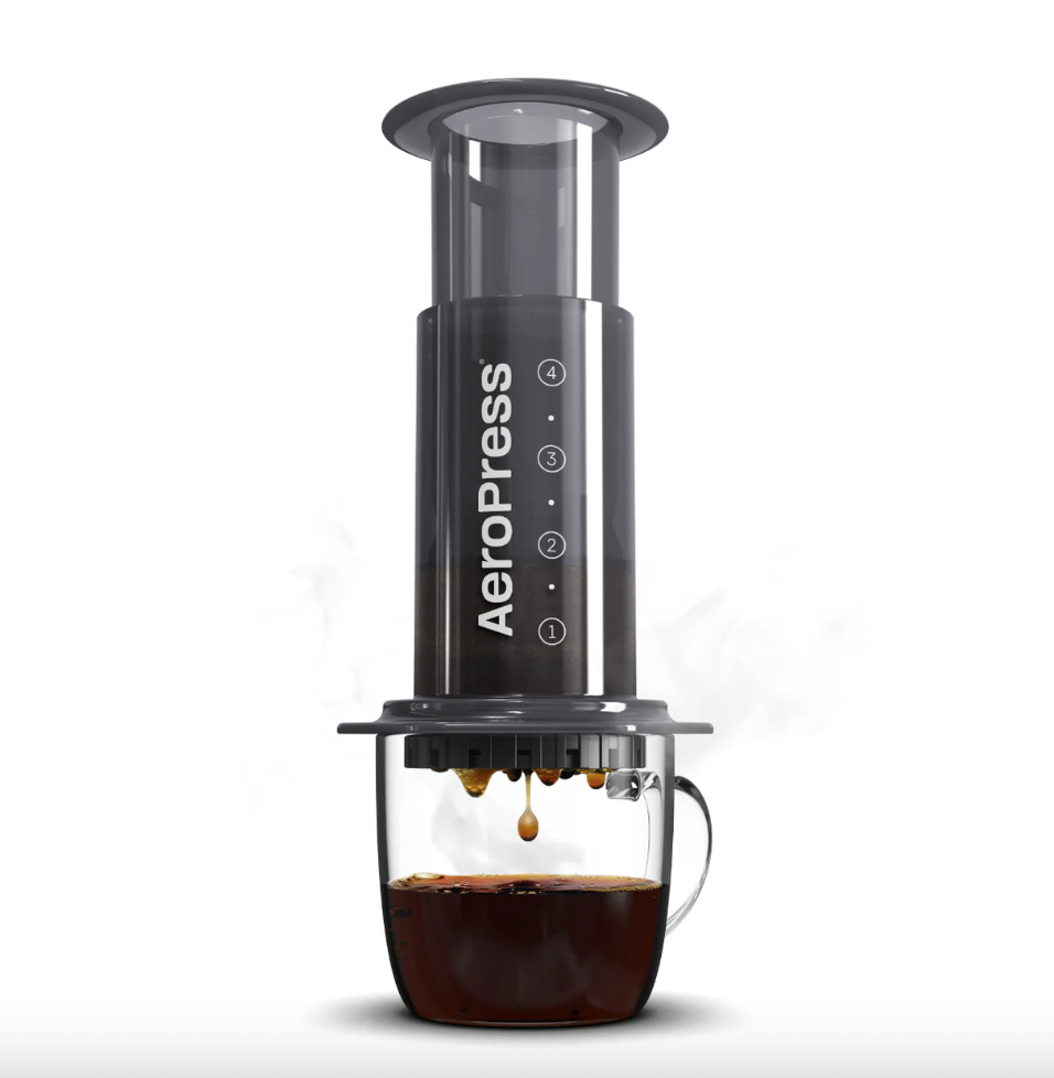 AeroPress coffee maker brewing black coffee into a clear glass cup