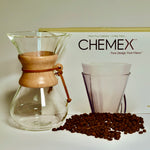 Chemex coffee maker with filter box and whole coffee beans on white background