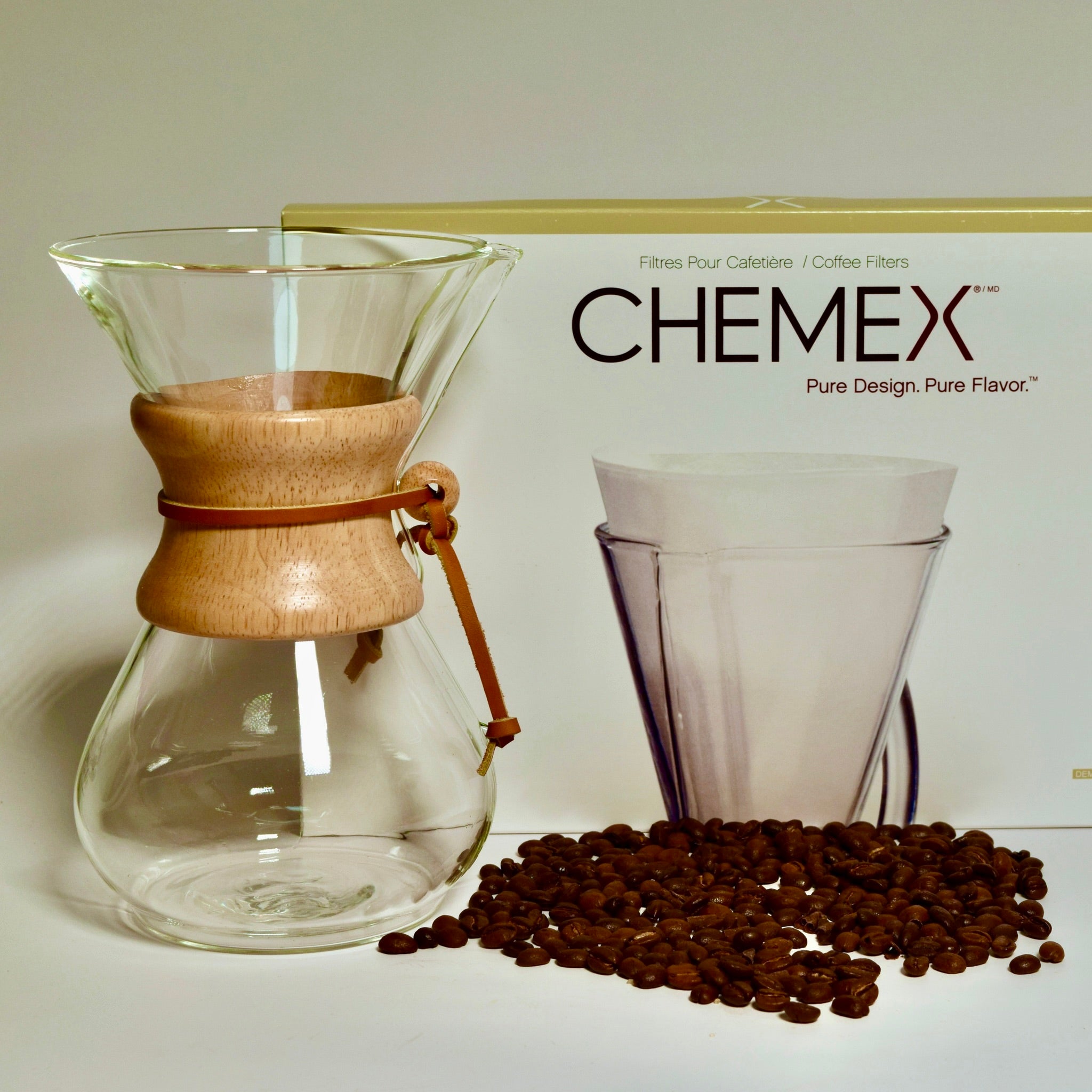 Chemex coffee maker with filter box and whole coffee beans on white background