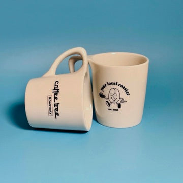 Two Coffee Tree Roastery mugs showing logo and local roaster designs