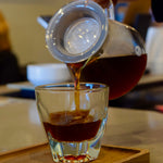 Fresh pour-over coffee being served into a glass, highlighting clarity and colour